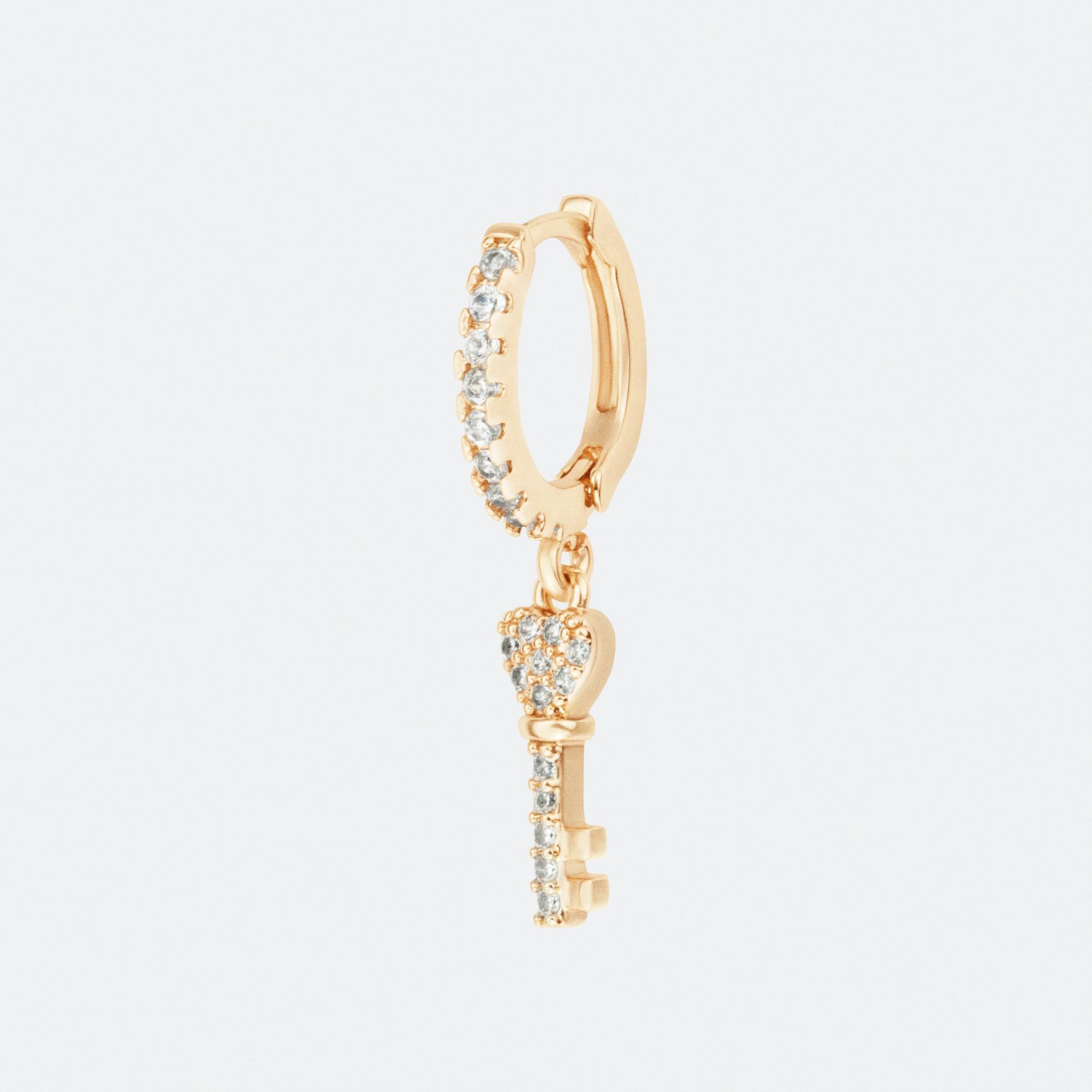 The Amuletum hoop earring by Ocarina, an 18K gold-plated design featuring a sparkling zircon-encrusted hoop with a delicate dangling key charm. A symbolic jewelry piece representing mystery and opportunity, displayed against a clean white background.