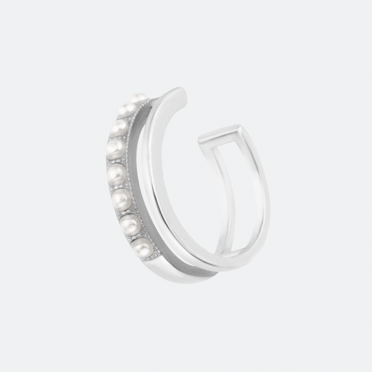 A modern silver ear cuff by Ocarina, featuring a sleek open-band design adorned with small pearls along the outer edge. A statement jewelry piece with a contemporary and elegant touch, displayed against a clean white background