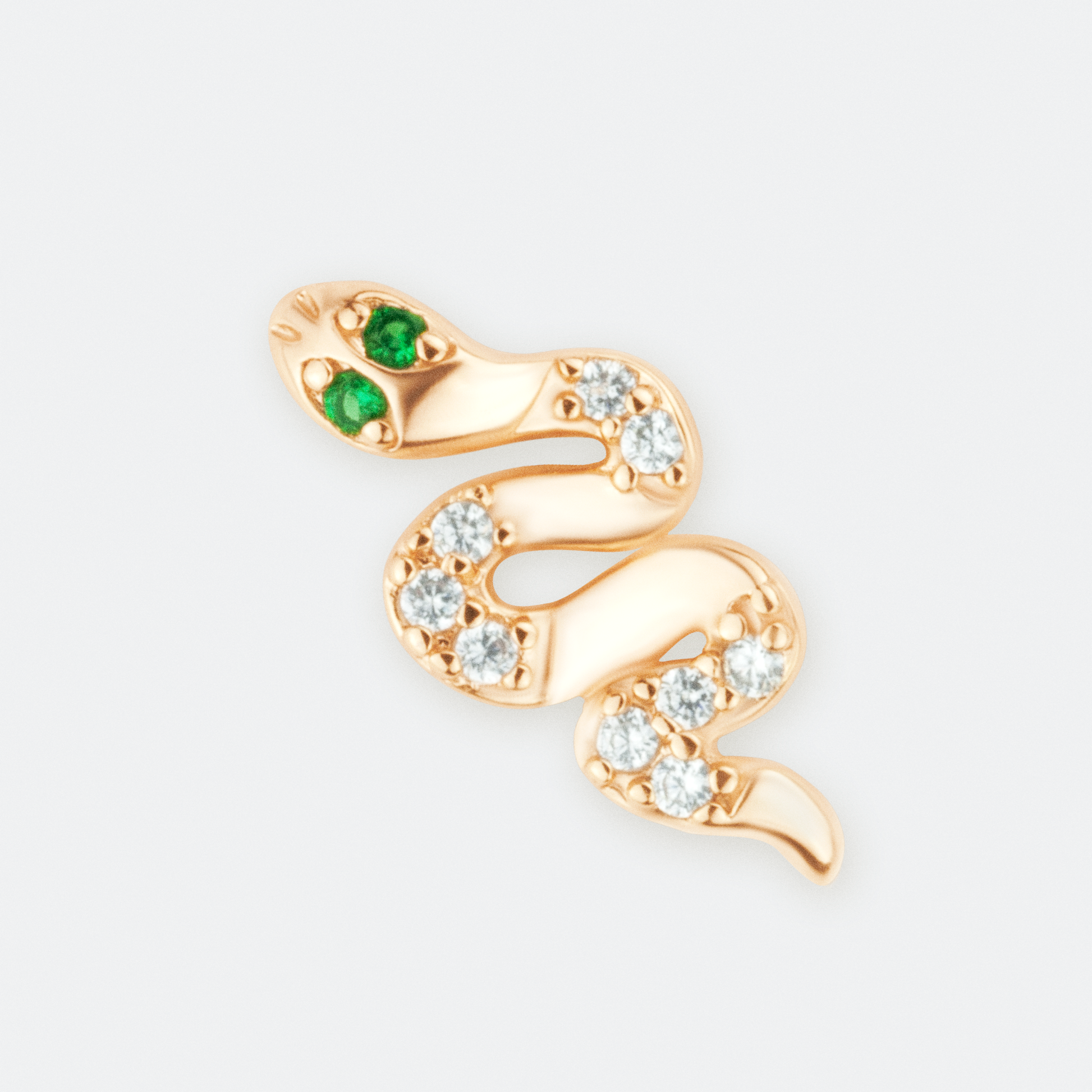 The Venefica earrings by Ocarina, 18K gold-plated snake-shaped stud earrings adorned with shimmering zircon stones and striking green gemstone eyes. A bold and mystical jewelry piece symbolizing transformation and power, displayed against a clean white background.